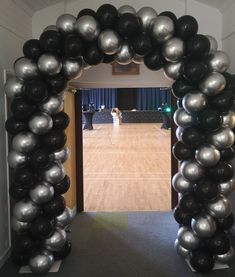 an arch made out of black and silver balloons