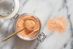 a glass jar filled with brown sugar next to a spoon on top of a marble counter