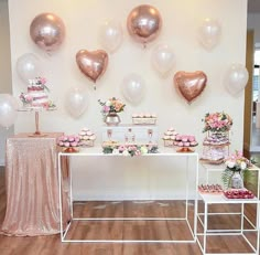 the dessert table is decorated with pink and white flowers, cupcakes, and heart - shaped balloons