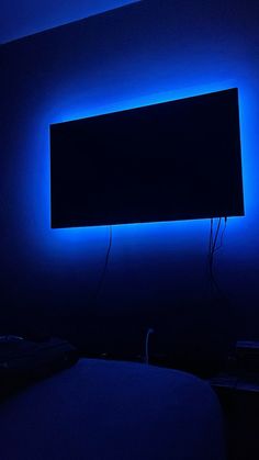 a dark room with blue lighting and a flat screen tv on the wall above it