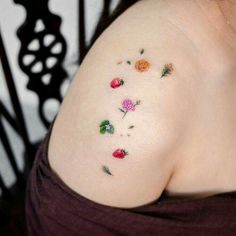 a woman's shoulder with small flowers and leaves on her left side, which is covered in tiny tattoos