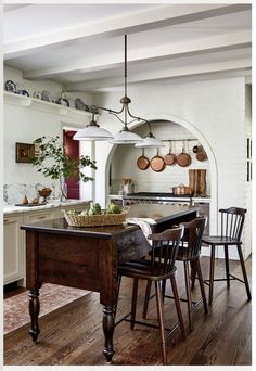 a kitchen with an island and wooden chairs in front of the countertop, along with hanging pots on the wall