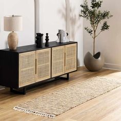 a living room with a rug, vases and a lamp on the sideboard