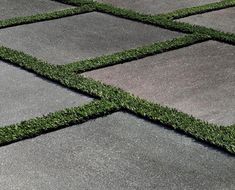 an outdoor area with grass and cement tiles on the ground, as if it were made from artificial turf