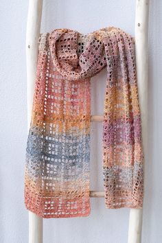 a multicolored scarf is hanging on a white ladder against a white wall,