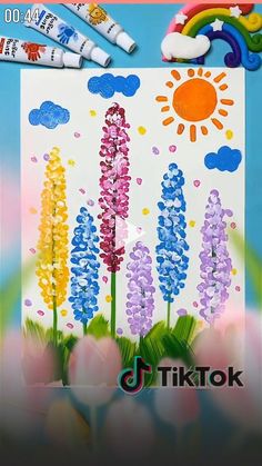 an art project with flowers and clouds painted on paper