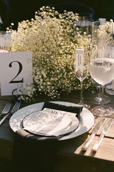 the table is set with two glasses of wine and place settings for guests to enjoy