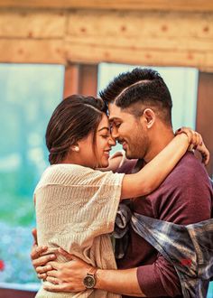 a man and woman embracing each other in front of a window