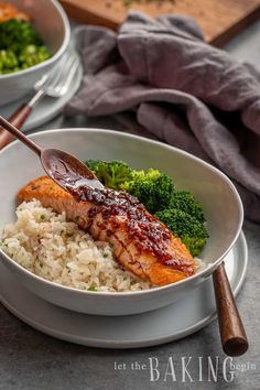 a bowl filled with rice, broccoli and salmon on top of a table