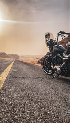 the motorcycle is parked on the side of the road in the middle of the desert