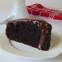 a piece of chocolate cake on a white plate with a red and white napkin next to it