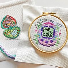 two cross - stitch designs are sitting next to each other on top of white napkins