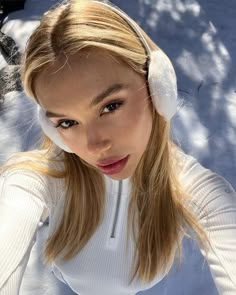 a woman with headphones on is posing for a photo in the snow, looking at the camera