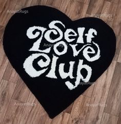 a black heart shaped rug with the words self love club written in white on it