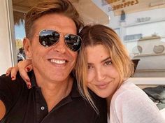 a man and woman are posing for a selfie in front of a store window