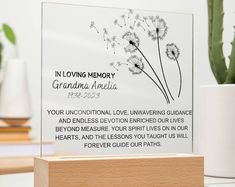 a memorial plaque with a dandelion in the center on a table next to a potted plant