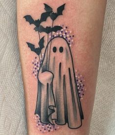 a black and white tattoo with a ghost holding a spooky bat next to a flower