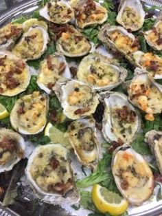 a platter filled with lots of oysters on top of lettuce and lemon wedges