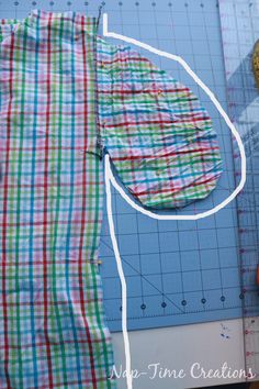 a pair of scissors next to a piece of fabric on top of a cutting board