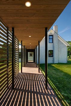 a long covered walkway leading to a house with a white building in the back ground