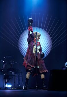 a woman standing on top of a stage in front of a microphone and some lights