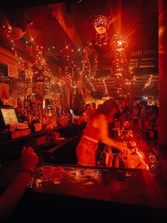 people are sitting at a bar with lights hanging from the ceiling and decorations on the walls