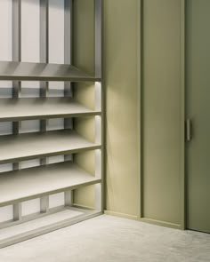 an empty book shelf in the corner of a room with green walls and white flooring