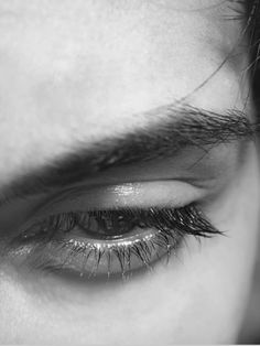 the eye of a person with long eyelashes and black hair is seen in this close up photo