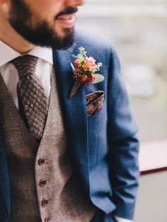 a man wearing a suit and tie with flowers in his lapel