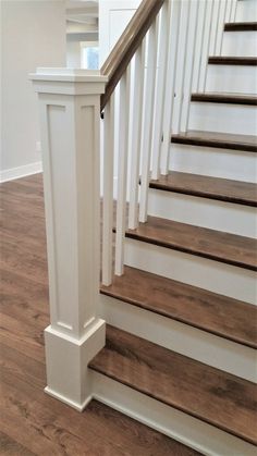 a white staircase with wooden handrails and wood flooring in a home's entryway