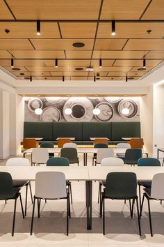 an empty conference room with tables and chairs in front of a large wall mural on the wall