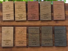 wooden business cards are lined up on a shelf in front of some trees and bushes