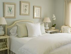 a white bed sitting in a bedroom next to two tables with lamps on top of it