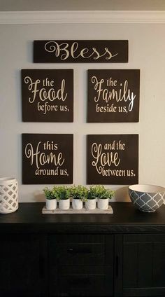 four signs are hanging on the wall above a black buffet table with white dishes and planters