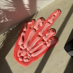 a red hand rug sitting on top of a wooden floor next to a person's feet