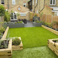 a small garden with grass and wooden planters in the back yard, surrounded by brick buildings