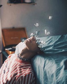 a person laying in bed with their head on the pillow and birds flying around them