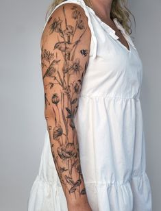 a woman with a tattoo on her arm and shoulder is posing for the camera while wearing a white dress