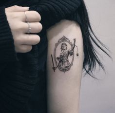 a lady justice tattoo on the left upper arm