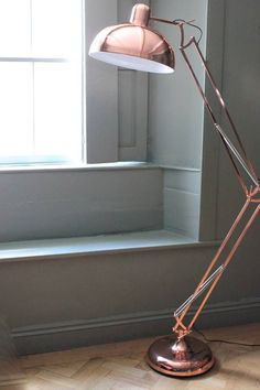 a floor lamp sitting on top of a hard wood floor in front of a window