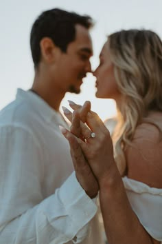 a man and woman standing next to each other with their hands together in front of the camera