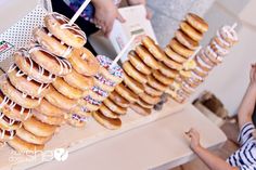 a table topped with lots of doughnuts on top of donuts next to people