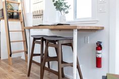 a kitchen table with two stools next to it and a ladder in the background