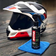 a motorbike helmet and cleaning cloth on a wooden table next to a bottle of motul