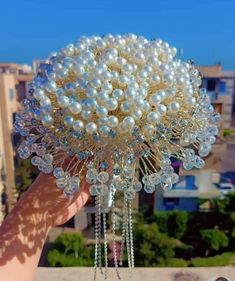 a person holding a bunch of pearls on top of a building with buildings in the background