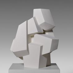 a white sculpture sitting on top of a metal block in front of a gray background