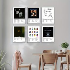 a dining room table and chairs with posters on the wall