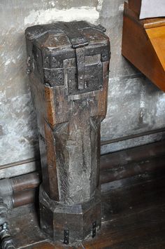 an old wooden box sitting on the floor next to a wall with peeling paint and wood trimming