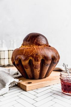 a loaf of bread sitting on top of a cutting board next to a jar of jam