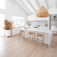 a white kitchen with two stools and an island